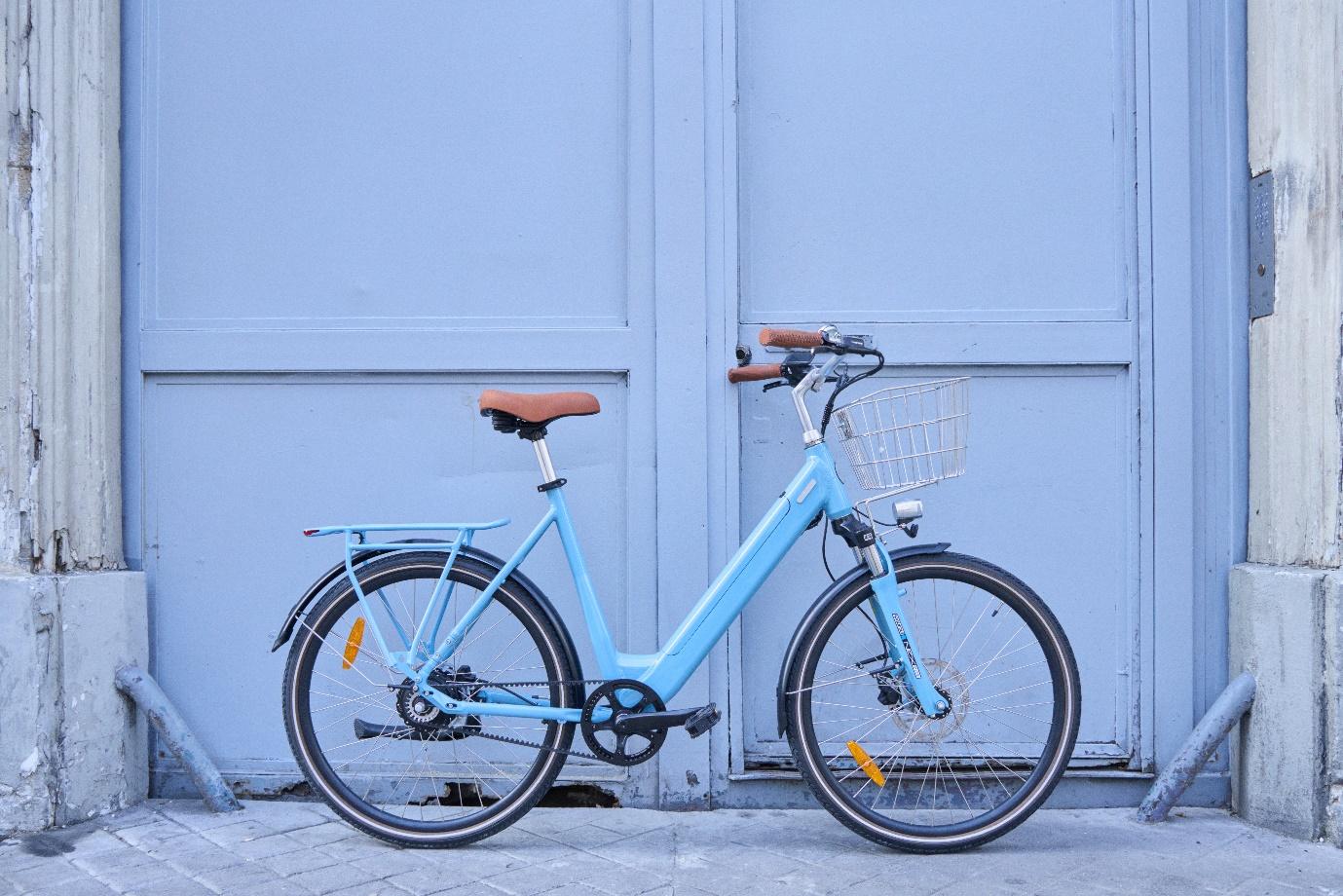 Un vélo électrique bleu contre une porte bleu